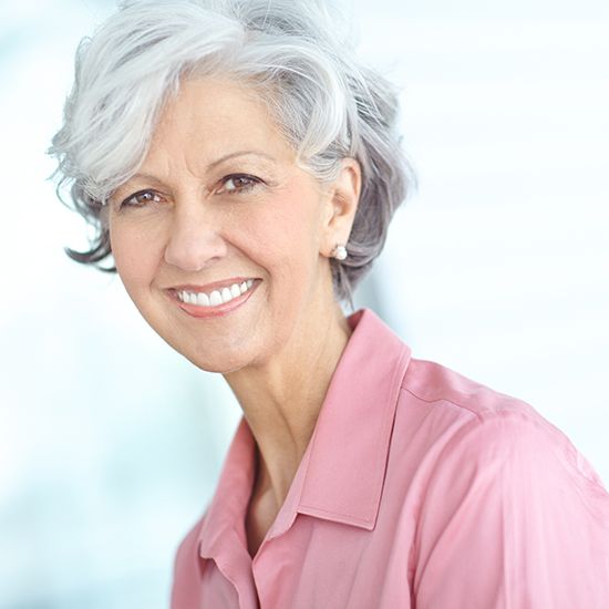 Woman with gray hair in pink shirt smiling