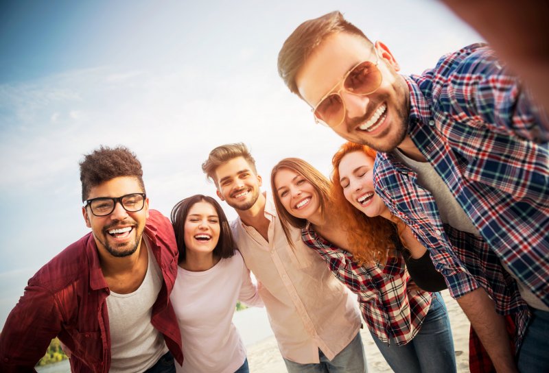 Friends on the beach smiling after preventing dental emergencies